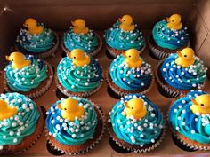 cupcakes with blue frosting and yellow rubber ducks in the water on top