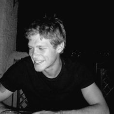 a man sitting at a table with a plate of food in front of him smiling