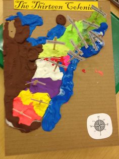 a map made out of colored paper on top of a cardboard box with scissors and tape