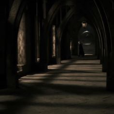 a dark hallway with light coming through the archways