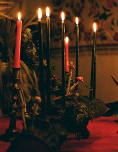 candles are lit on a table with red cloth