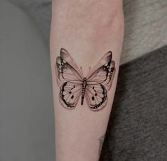 a black and white butterfly tattoo on the arm