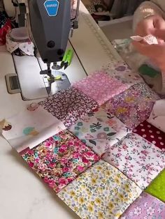 someone is using a sewing machine to sew quilts on the table top in front of them