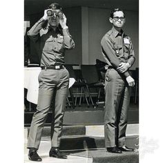 two men in uniforms are looking through binoculars