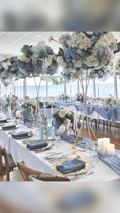 a table set with blue and white flowers in vases, plates and silverware