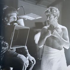 an old black and white photo of two people in front of a television set, one holding a camera