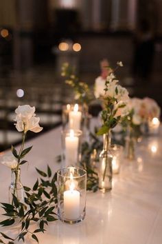 a long table with candles and vases filled with white flowers on top of it