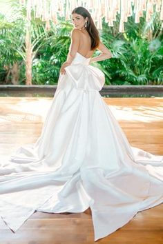 a woman in a white dress standing on a wooden floor with her back to the camera