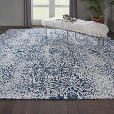 a blue and white area rug with a bench in front of a window on the floor