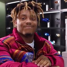 a man with dreadlocks sitting in front of a book shelf