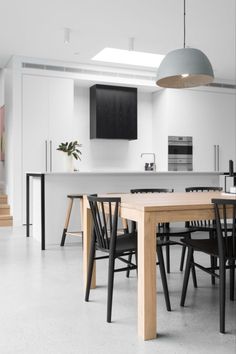 an open kitchen and dining room area with white walls, black chairs and wooden table