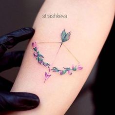 a woman's arm with an arrow and flowers on it