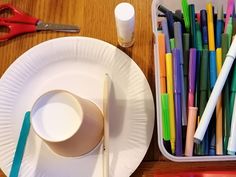 there are many different colored pens on the paper plate next to scissors and pencils