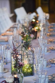 the table is set with clear wine glasses and flowers