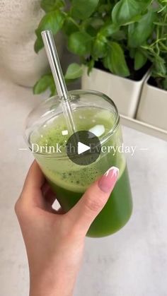 a person holding a green drink with a straw