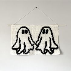 two black and white knitted birds hanging on a wall