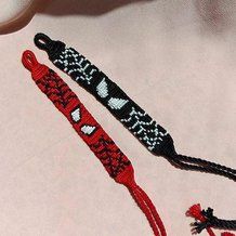 two red and black beaded items laying on top of a white cloth covered surface