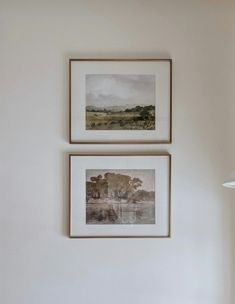 two framed pictures hang on the wall above a bed in a room with white walls