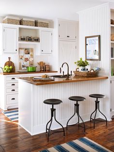 a kitchen with three stools in front of an island and white cabinets on the wall