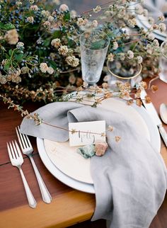 a place setting with silverware, flowers and napkins