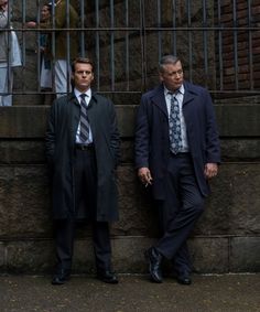 two men standing next to each other in front of a building with bars on it