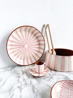 pink and white striped dishes with wooden utensils sitting on a marble countertop