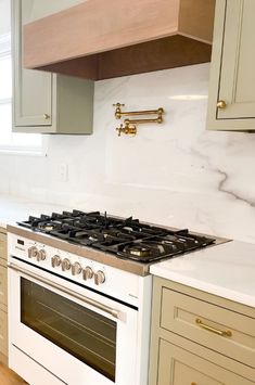 a white stove top oven sitting inside of a kitchen next to wooden cabinets and drawers