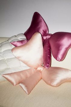 two pink pillows on top of a white bed