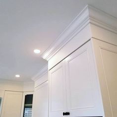 a kitchen with white cabinets and black counter tops in the center, along with recessed lighting