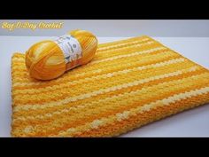 a crocheted blanket with yarn on it and a ball of yarn next to it