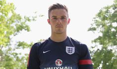 a soccer player poses for a photo in front of some trees and bushes on a sunny day