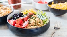 two bowls filled with different types of food on top of a wooden table next to silverware