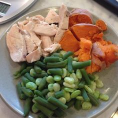 a plate with green beans, carrots and chicken on it next to a scale