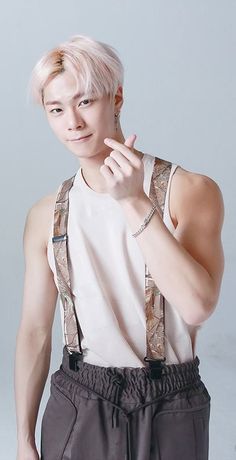 a young man with pink hair and suspenders posing for a photo in front of a white background