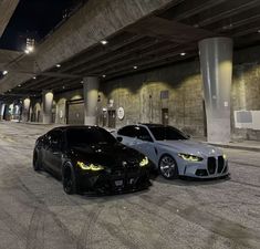 two cars parked next to each other in an empty parking lot at night with lights on