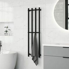 a white bath tub sitting next to a bathroom sink under a round mirror on the wall