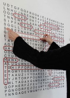 a man writing on a white wall with red and black letters in the shape of squares