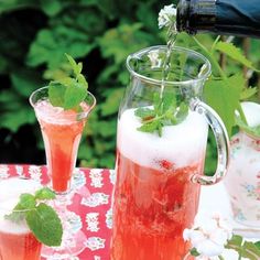 a pitcher filled with liquid pouring into two glasses