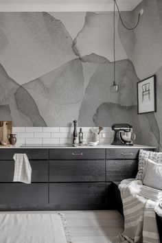 a black and white kitchen with an artistic wallpaper pattern on the back splashes