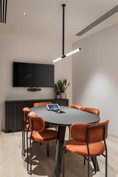 a conference room with orange chairs and a flat screen tv mounted on the wall above it