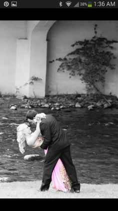 a man and woman kissing in front of a river