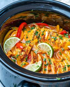 a crock pot filled with chicken, peppers and limes on top of a table