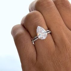 a woman's hand with a ring on it and a pear shaped diamond in the middle