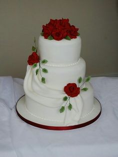 a three tiered wedding cake with red roses on it