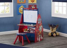 a child's toy easel with paw patrol pictures on the wall next to it