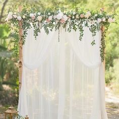 a white wedding arch with flowers and greenery