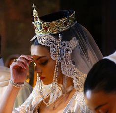 a woman wearing a tiara and holding a cell phone to her ear while standing next to another man