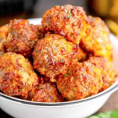 a white bowl filled with meatballs on top of a wooden table