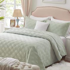 a bedroom with a large bed covered in green bedspread and white comforter