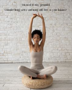 a woman sitting in a yoga position with her hands up